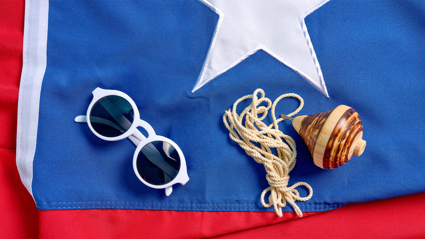 Lentes y trompo sobre la bandera de Chile en Fiestas Patrias