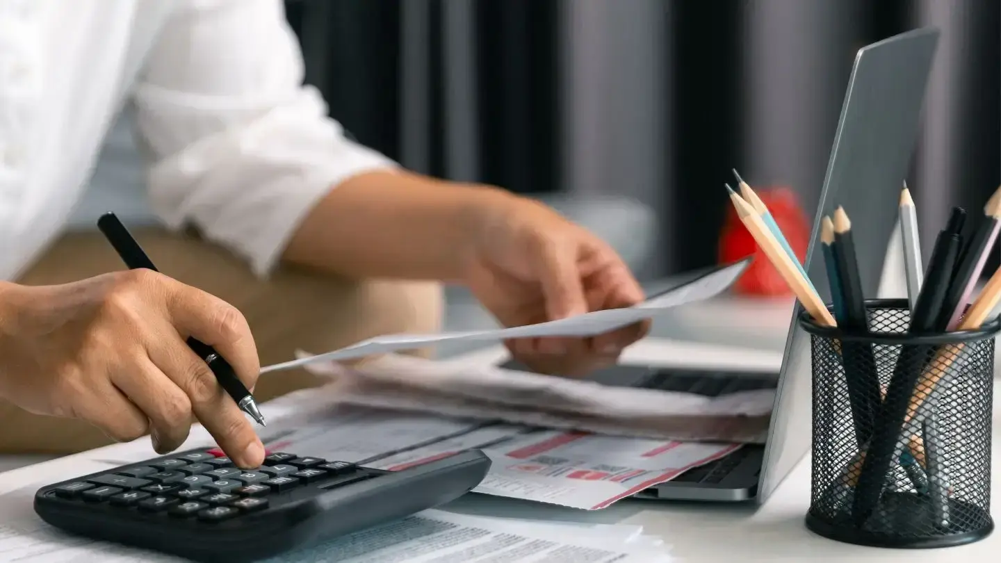 Contribuciones: Qué son y qué pasa si no las pago, hombre revisa documentos y utiliza calculadora