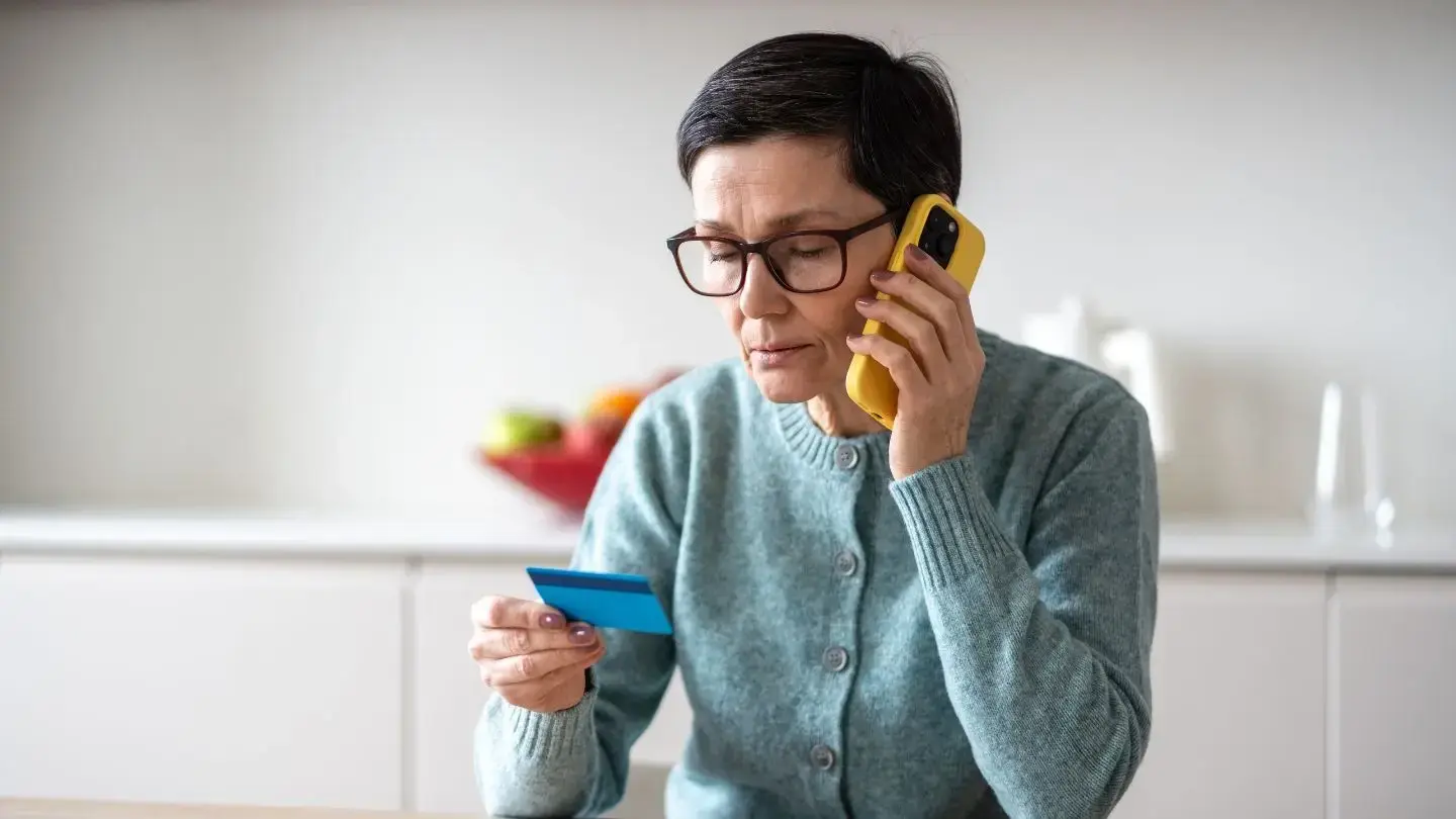 ¿Conviene repactar deudas? Mujer llamando por teléfono mirando su tarjeta