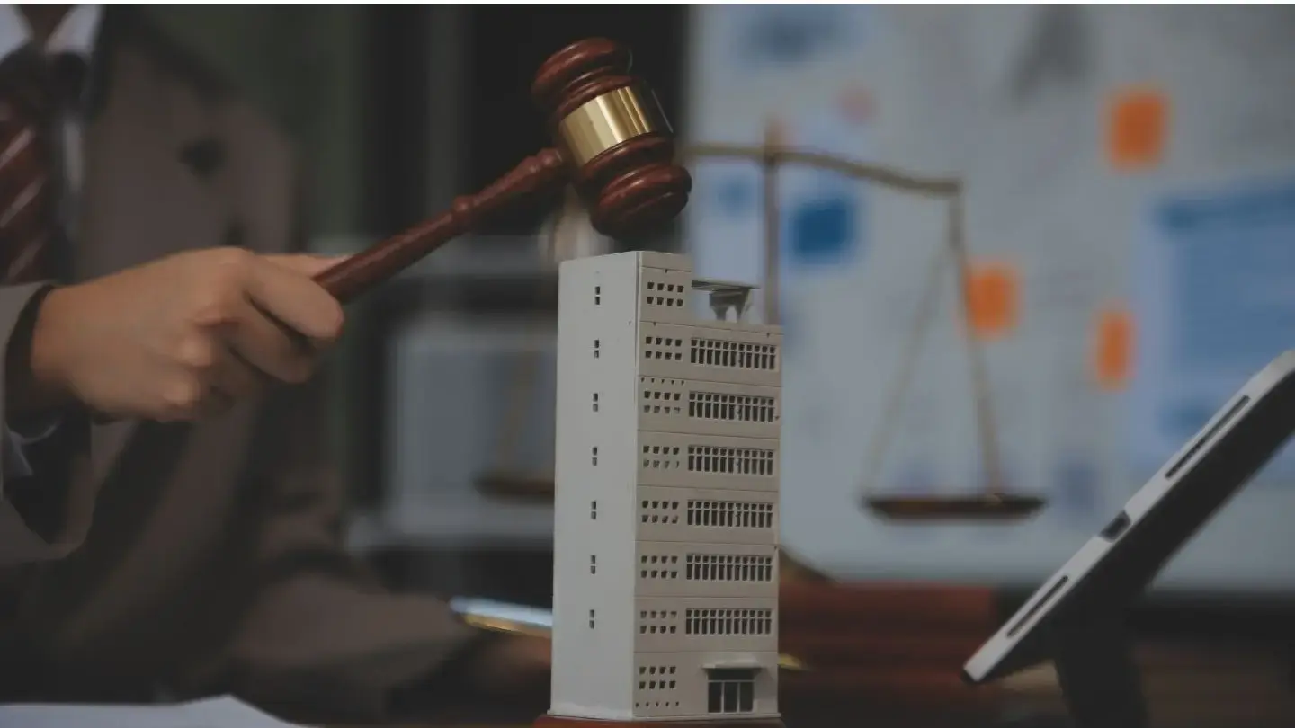 Diferencia entre embargo, retiro y remate de bienes. Mazo judicial golpeando una maqueta de edificio