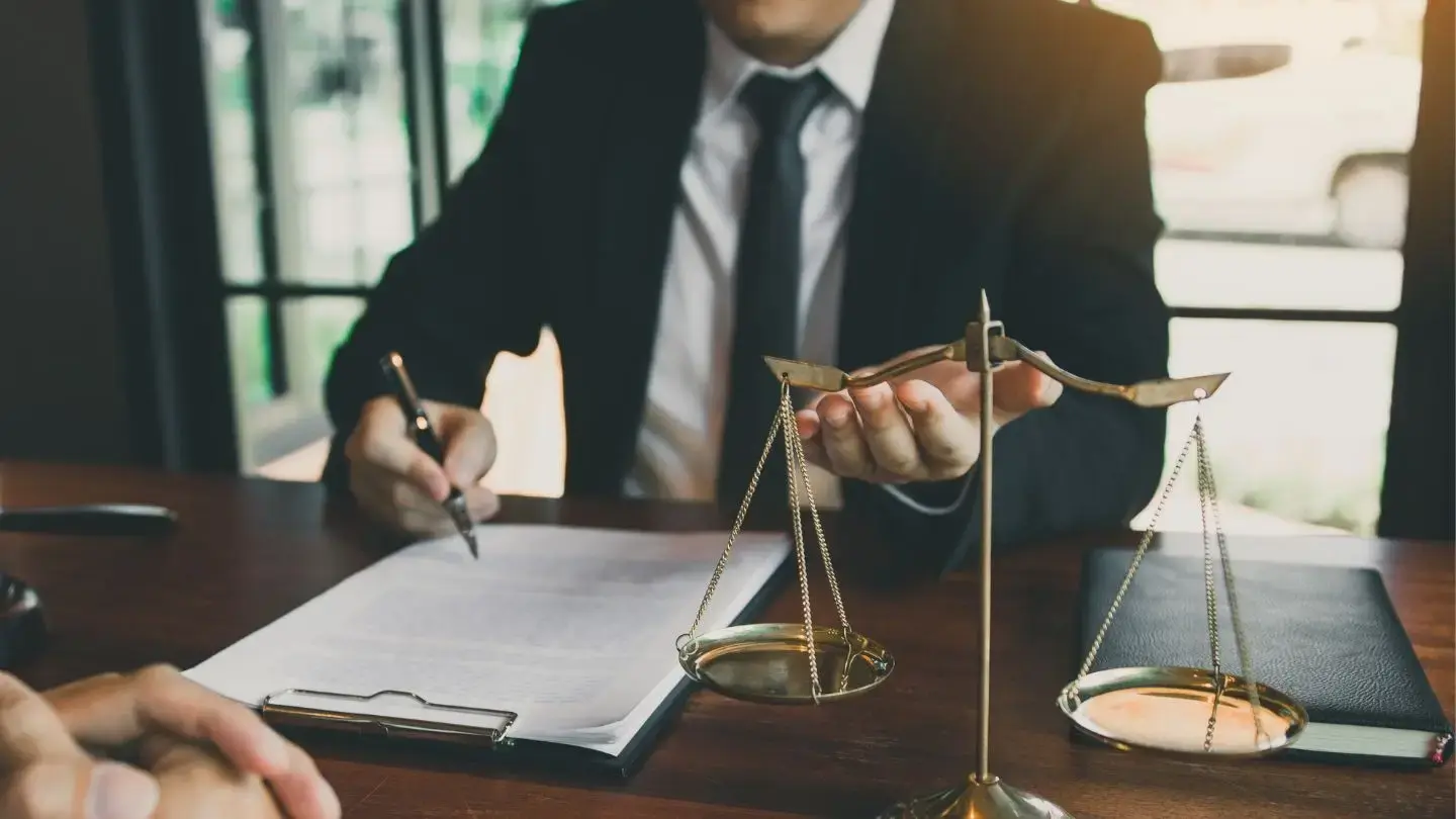 Qué hago si me notifican mal una demanda. Hombre firma documentos junto a la balanza de la justicia