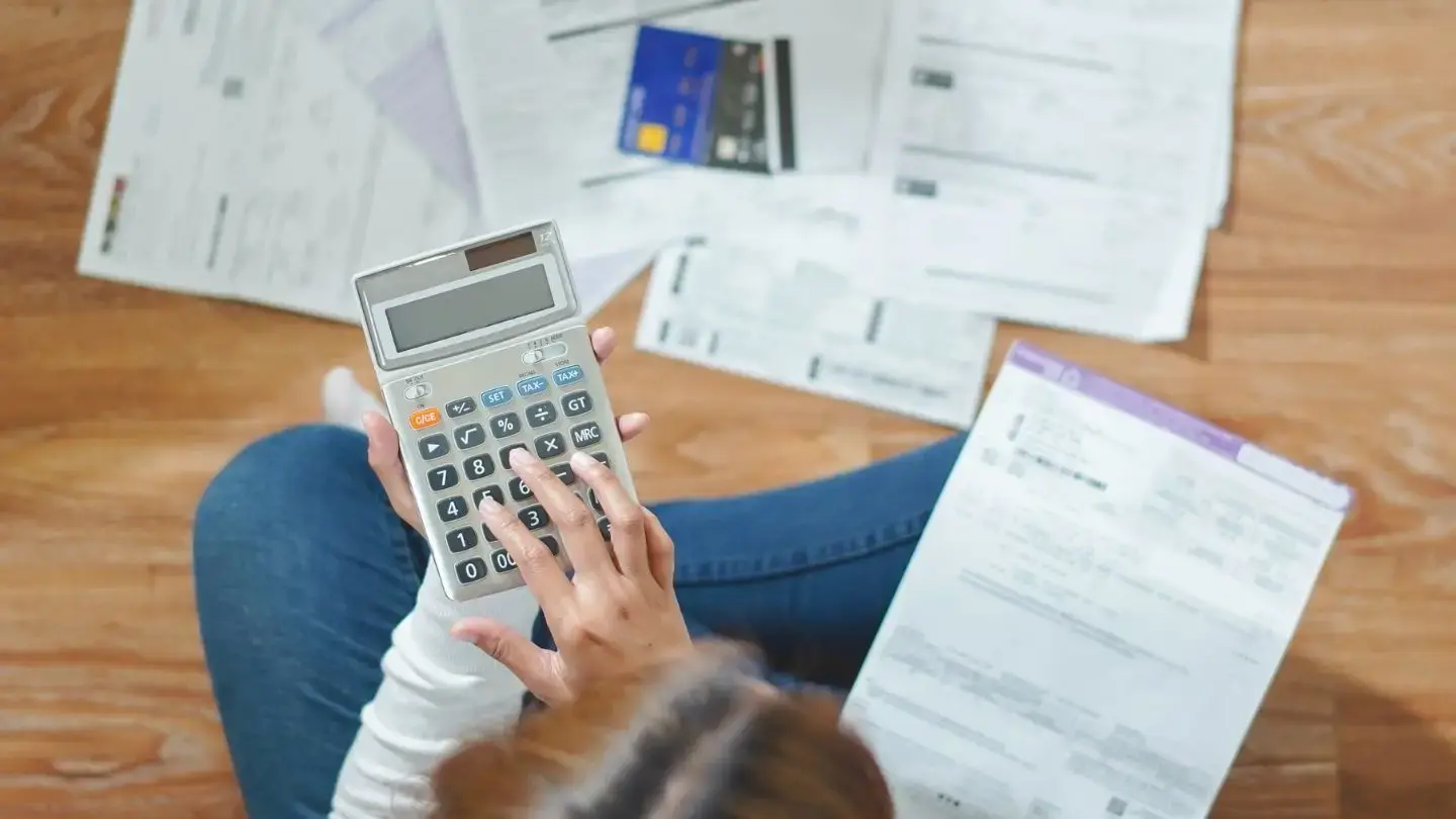 Tesorería General de la República: guía práctica TGR. Mujer utiliza calculadora sentada en el piso