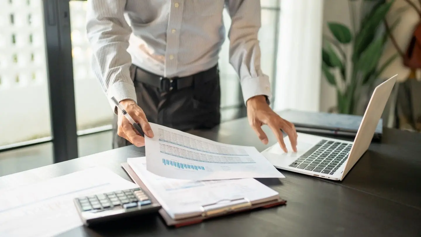 Qué es el boletín comercial. Hombre revisando documentos y un computador